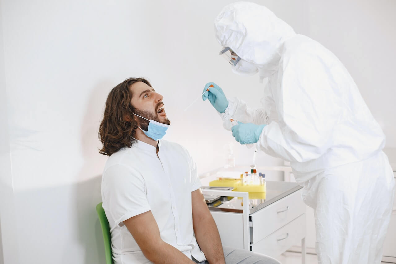 A doctor doing an oropharyngeal swab test on a man