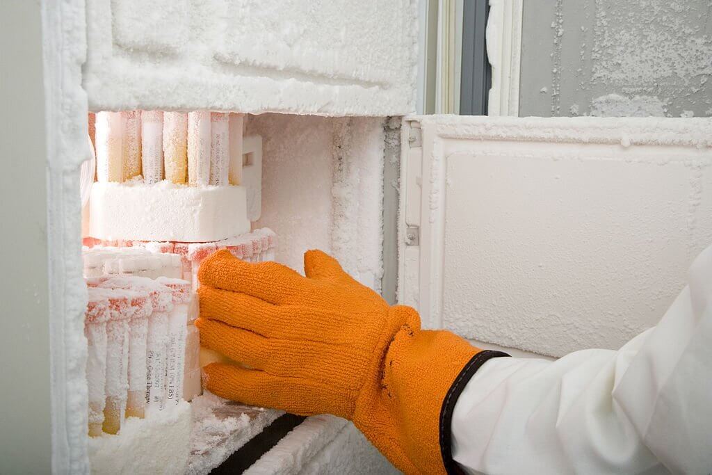  a researcher's arm retrieving medical samples from a freezer