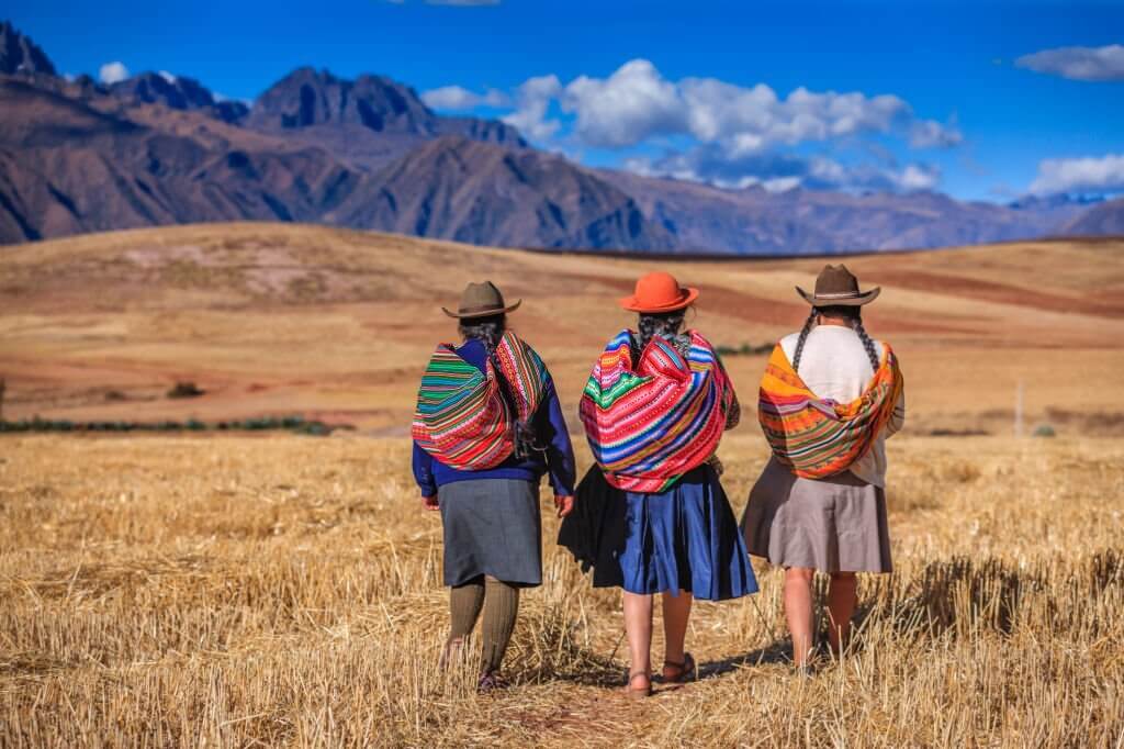 Peruvian women in national clothing crossing field