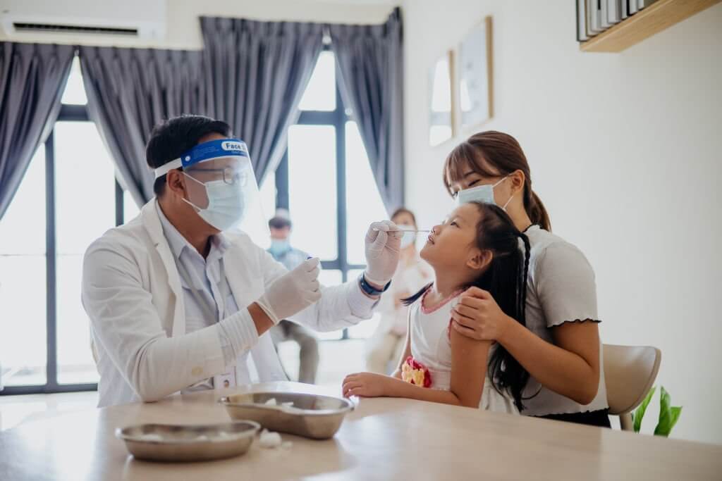  an Asian woman bring her daughter to get a nasal swab for coronavirus test from a healthcare worker