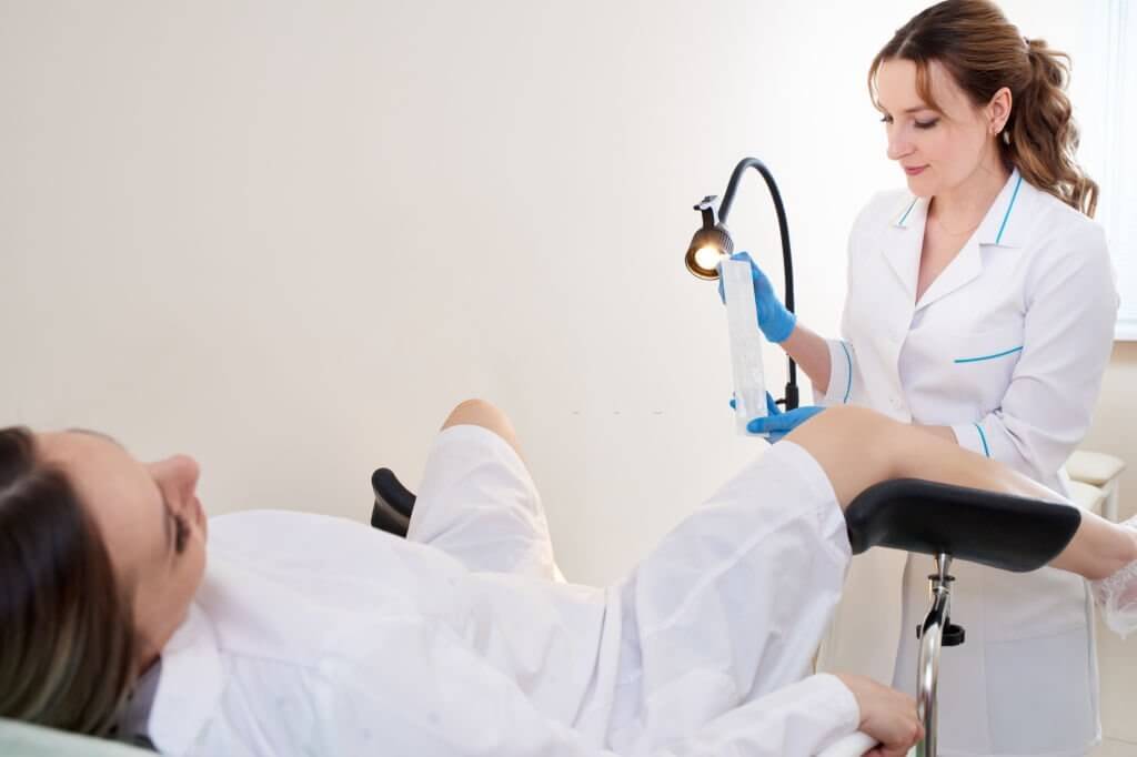 Gynecologist using vaginal swab for STD testing. Woman in gynecological chair