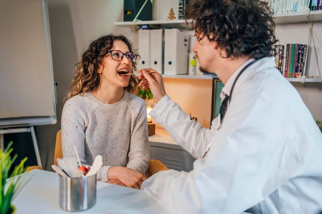 Doctor taking an oral swab from the female patient for analysis