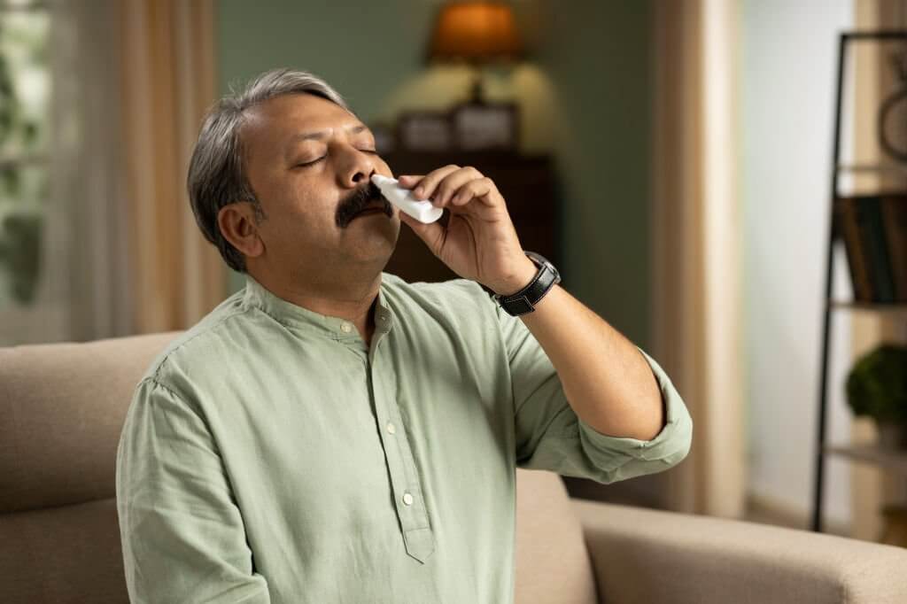Senior man with a nasal spray, using nose drops