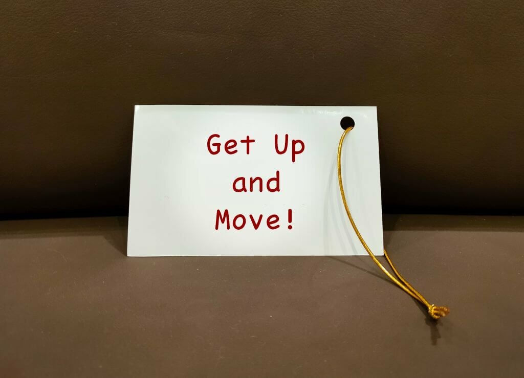 Reminder card on sofa with handwritten text Get Up and Move, to beat sedentary lifestyle and move around