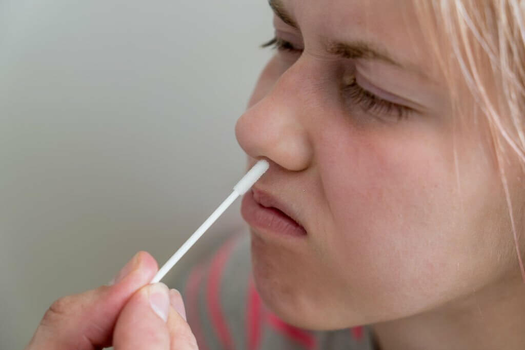 Teenage girl doing rapid antigen test nasal swab.