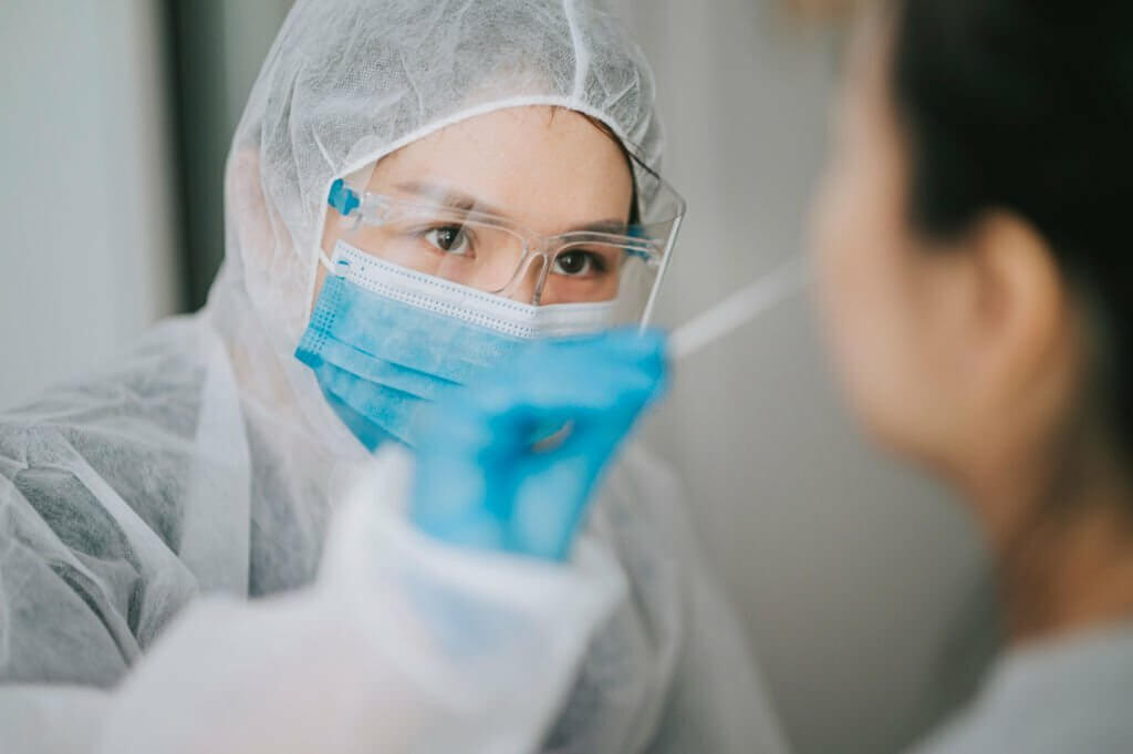 Asian chinese female doctor with PPE taking nasal sampling swab from patient