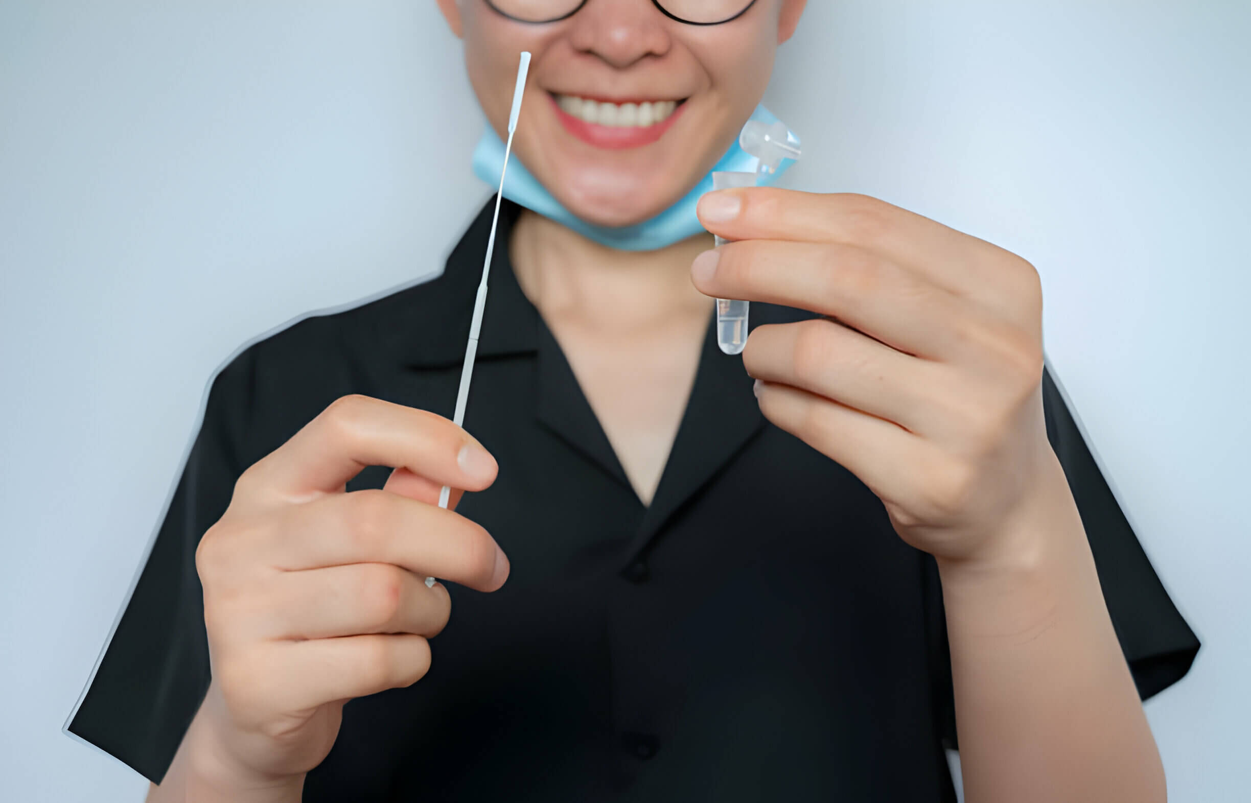 Smiling woman holding a disposable sterile flocked swab with a collect tube before doing swab