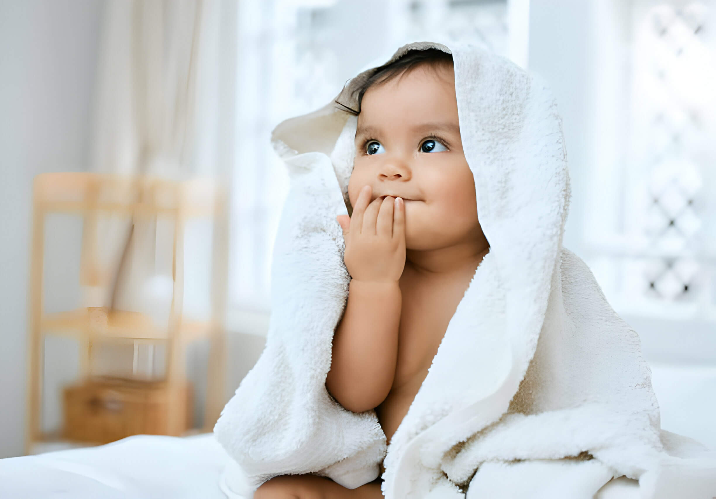 an adorable baby covered in a towel after bath time