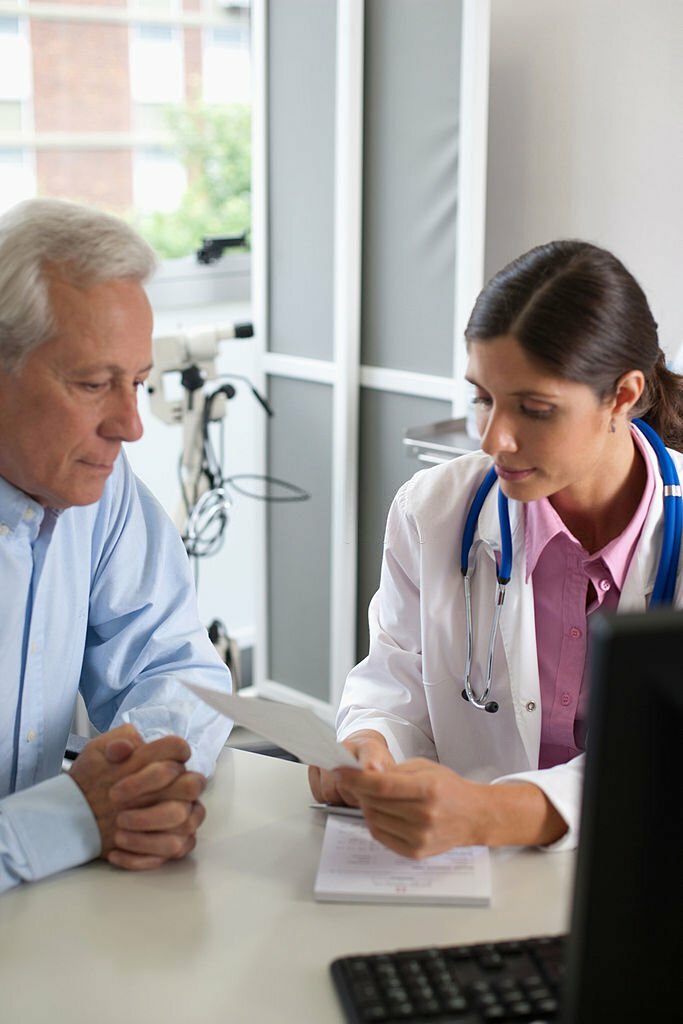 Doctor sitting in office with patient talking and holding paper