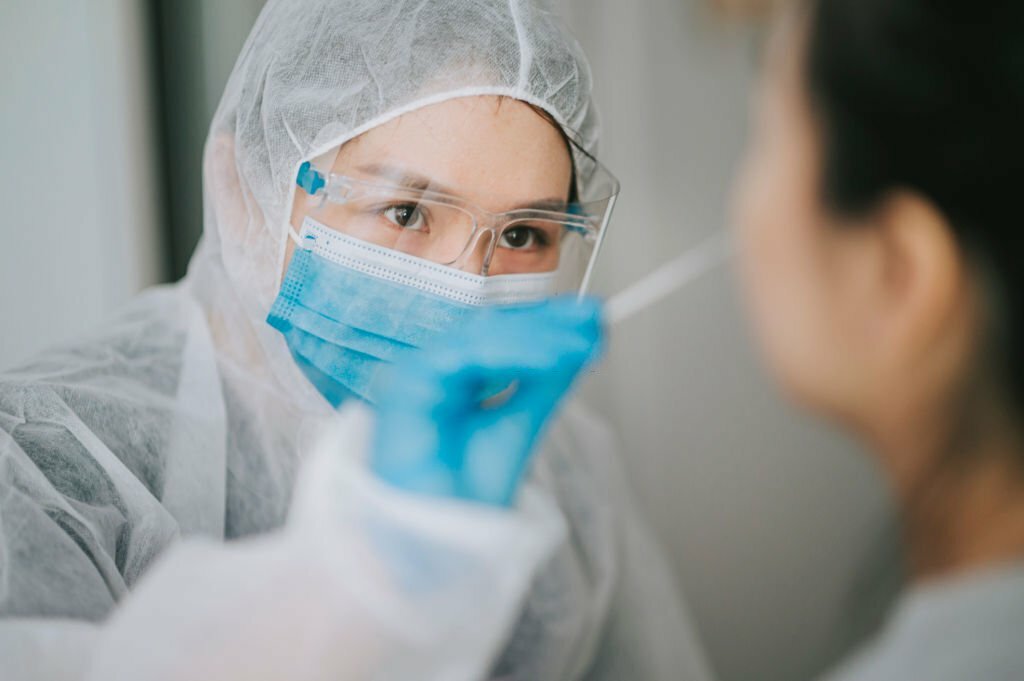 Asian healthcare professional is using a nasopharyngeal swab to collect specimen from a child